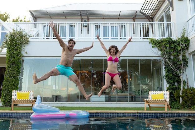 Happy young couple jumping in the swimming pool