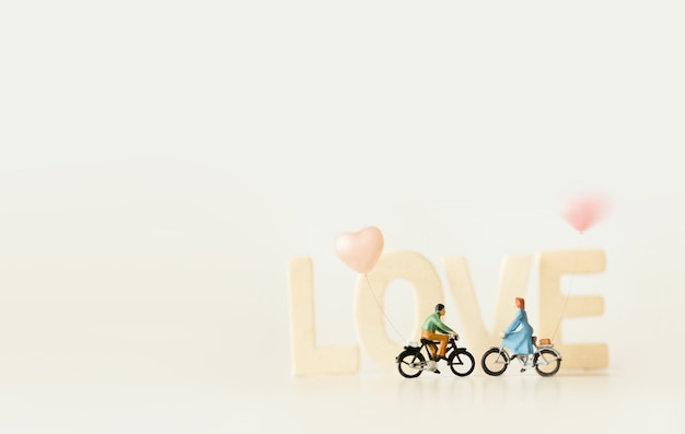 Happy young couple  (miniature) on cycle ride  with  "LOVE" text.Valentine's day background with vintage color theme.