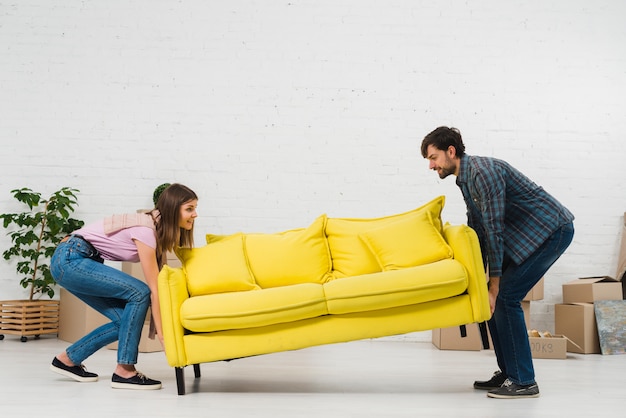 Happy young couple placing the yellow sofa in the living room