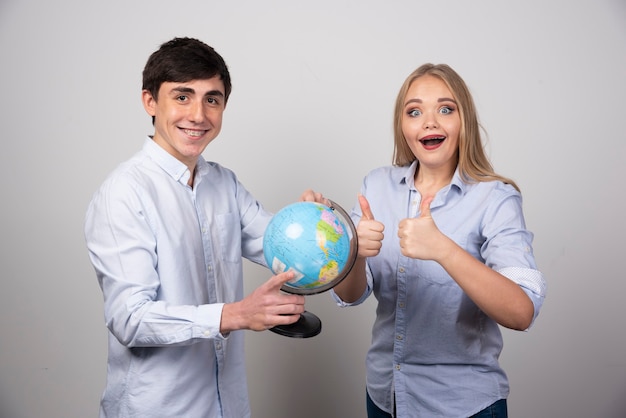 Happy young couple planning their anniversary destination holding up a globe.