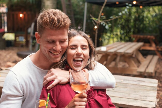 Photo happy young couple playing and cuddling at outdoor bar restaurant in the woods