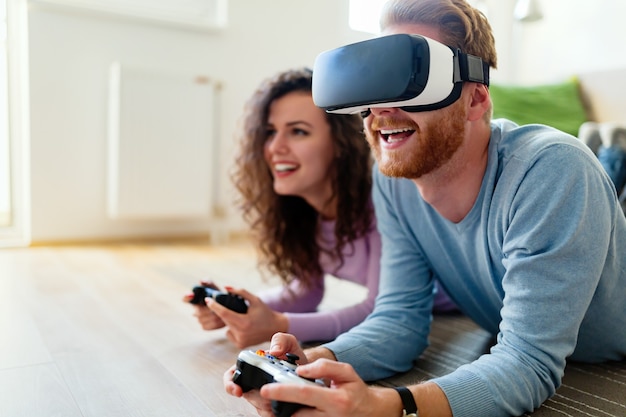 Happy young couple playing video games with virtual reality headsets at home