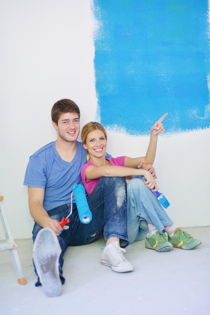 happy young couple relax after painting white wall in green and blue color in their new home