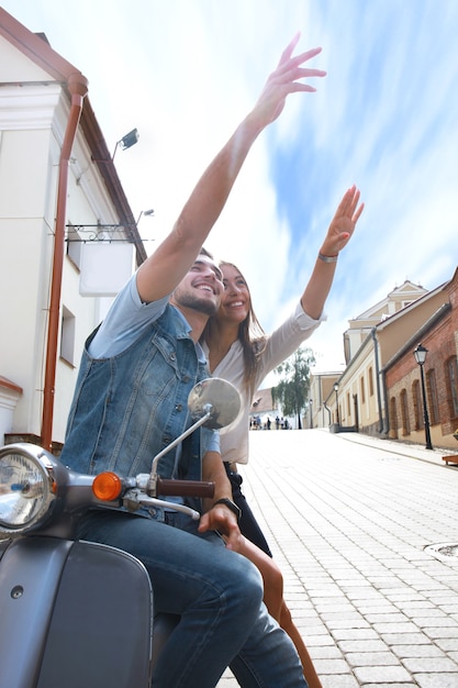 Photo happy young couple riding scooter in town. handsome guy and young woman travel. adventure and vacations concept.