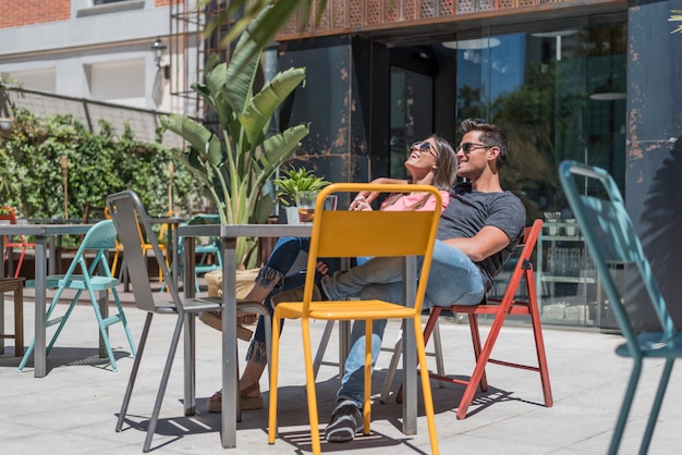 Happy young couple seating relaxed in a restaurant terrace