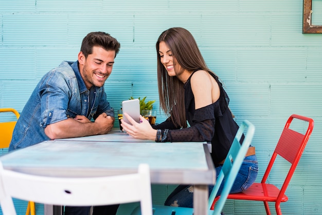 Happy young couple seating in a restaurant with a smartphone