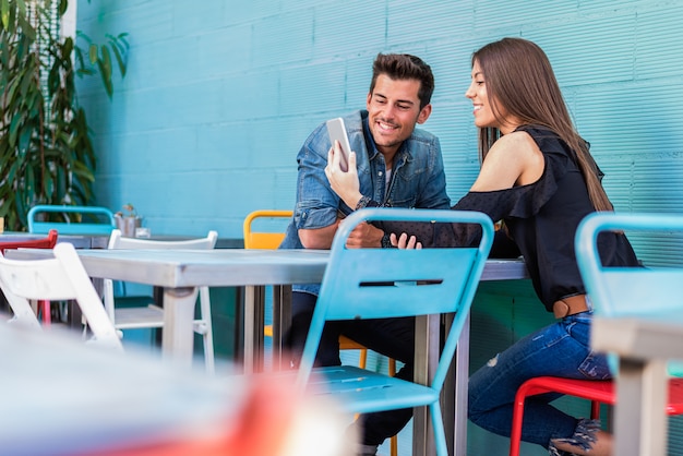 Happy young couple seating in a restaurant with a smartphone