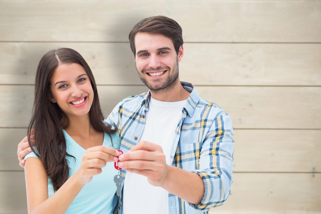 Happy young couple showing new house key against bleached wooden planks background