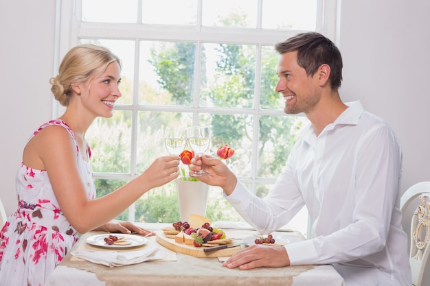 Happy young couple toasting wine glasses over food