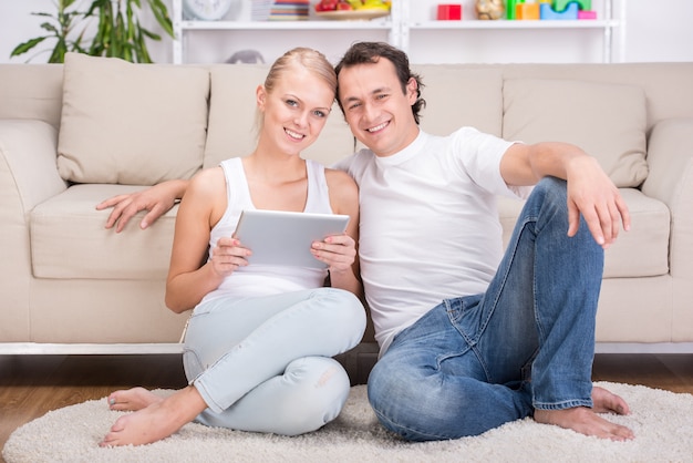 Happy young couple with tablet at home.