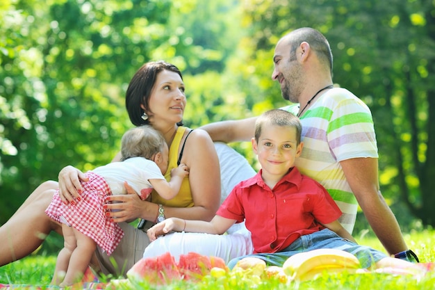 happy young couple with their children have fun at beautiful park outdoor in nature