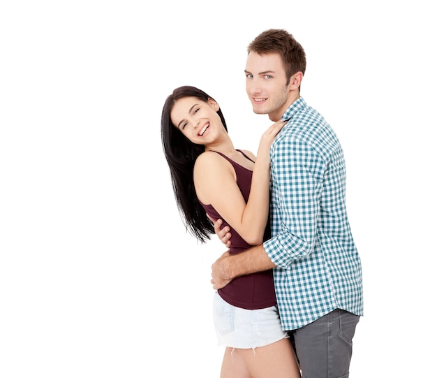 Happy young couple with white perfect smile in summer clothing embracing and looking camera on white background