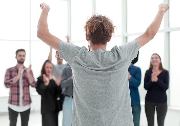 Happy young employee standing in front of applauding colleagues