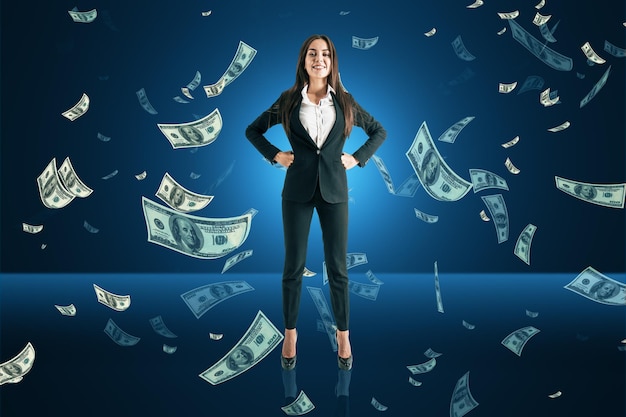 Happy young european business woman with falling dollar bills on blue background Success lottery win and money concept