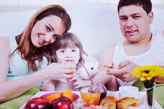 happy young family eat breakfast in bed at morning