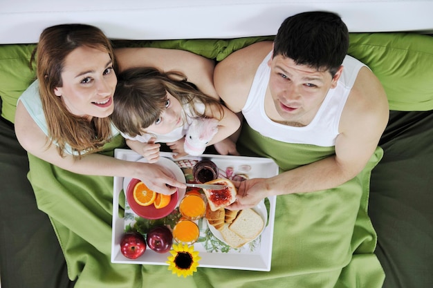 happy young family eat breakfast in bed at morning