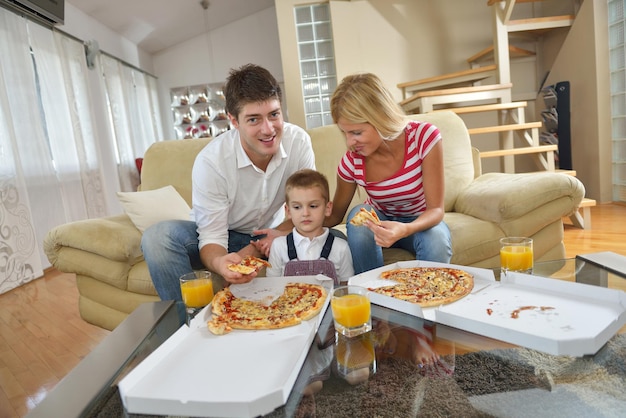 happy young family eating tasty pizza with cheesa and dring healthy and fresh orange juice