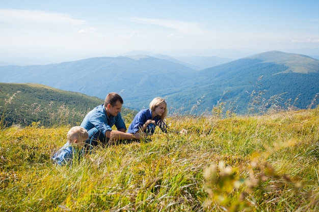 Happy young family gathers berries in the mountains