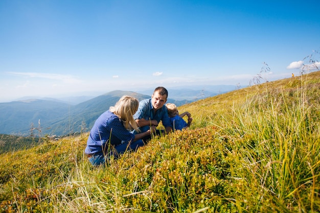 Happy young family gathers berries in the mountains