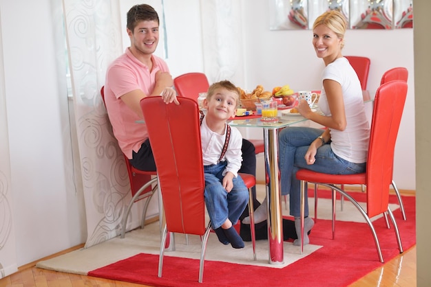 happy young family have healthy breakfast at kitchen with red details on bright morning light