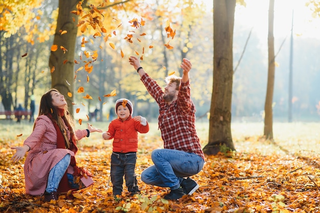 Happy young family spending time outdoor in the autumn park