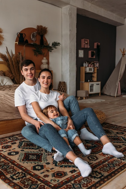 A happy young family spends time together in a home interior A beautiful happy family spending time together at home A young married couple with their cute daughter The family spends time at home