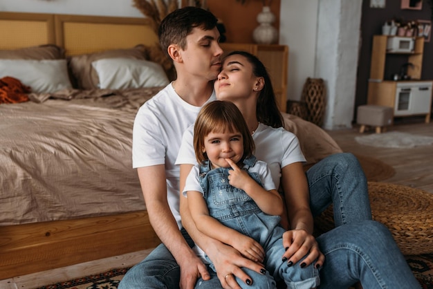 A happy young family spends time together in a home interior A beautiful happy family spending time together at home A young married couple with their cute daughter The family spends time at home