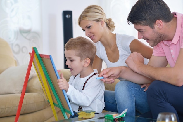 happy young family teach leassons and prepare their son for school while draw on board at home