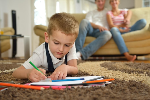 happy young family teach leassons and prepare their son for school while draw on board at home