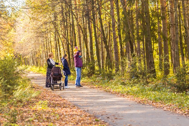 Happy young family walking down the road outside in autumn nature