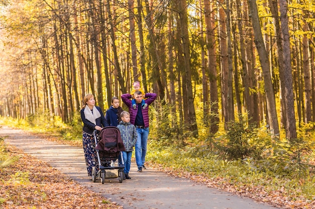 Happy young family walking down the road outside in autumn nature