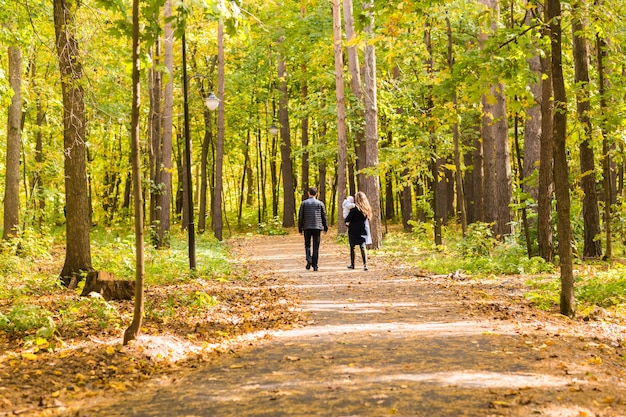 Happy young family walking down the road outside in autumn nature