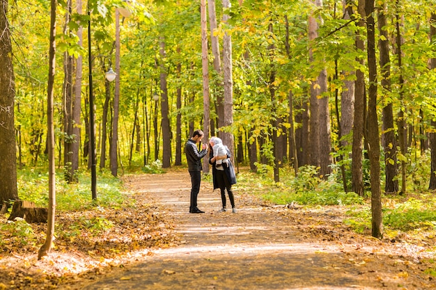 Happy young family walking down the road outside in autumn nature