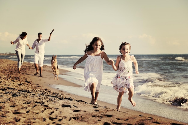 happy young family in white clothing have fun and play with beautiful dog at vacations on beautiful beach