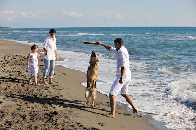 happy young family in white clothing have fun and play with beautiful dog at vacations on beautiful beach