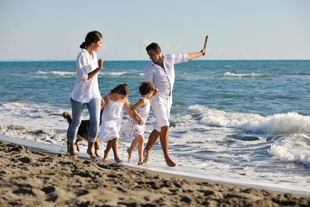 happy young family in white clothing have fun and play with beautiful dog at vacations on beautiful beach