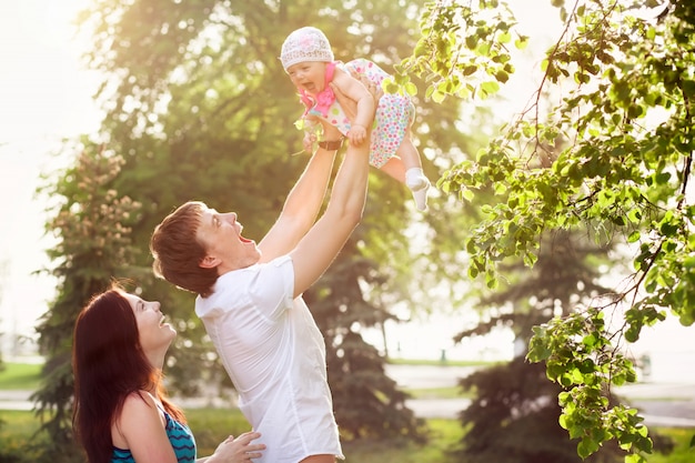 Happy young family with child resting outdoors in summer park