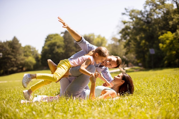 Happy young family with cute little daughter having fun in the park on a sunny day