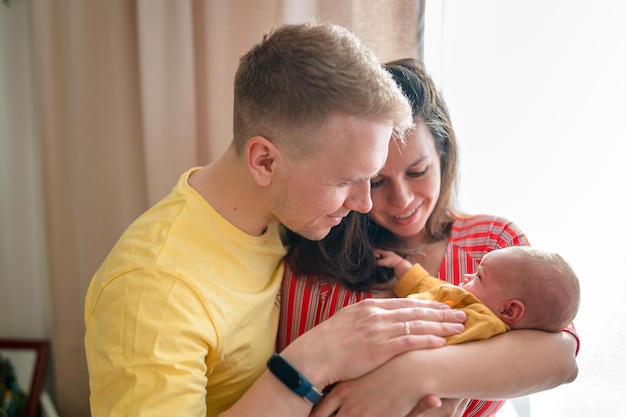 Happy young family with dad mom and newborn baby in the baby's room