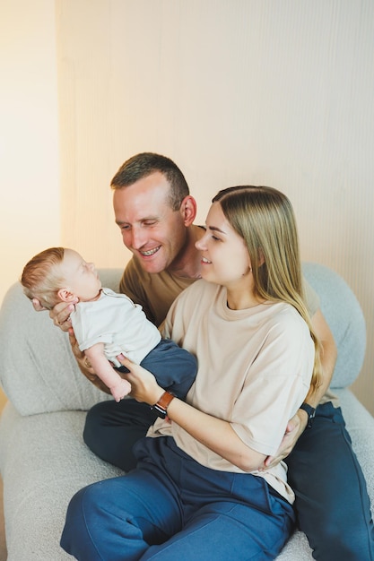 Happy young family with a newborn baby Beautiful mother and father kissing their child Parents and smiling child in arms isolated over white background