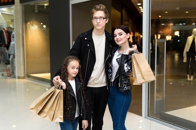 Happy young family with paper bags shopping at the Mall Shop Windows with clothes