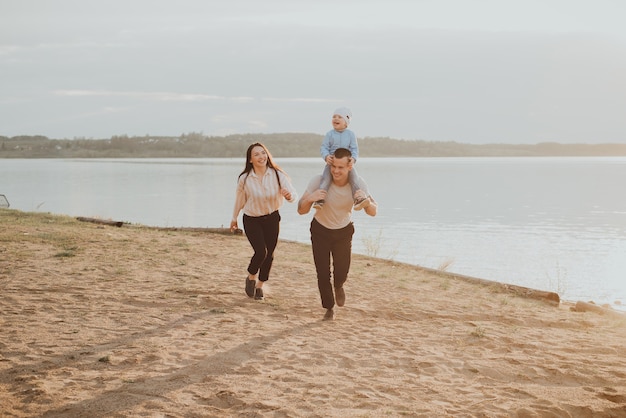 Happy young family with their son playing and enjoying on the beach in the summer by the water