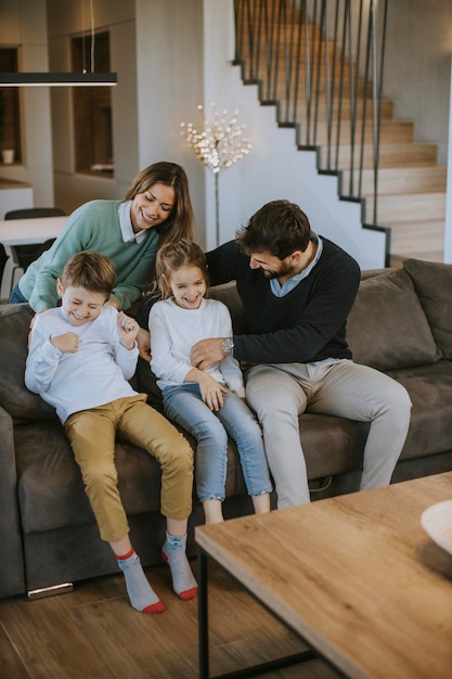 Happy young family with two kids enjoy time together on couch in living room