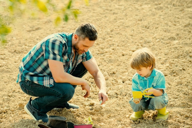 Happy young father planting a tree while his little son helping him father and son gardening in gard