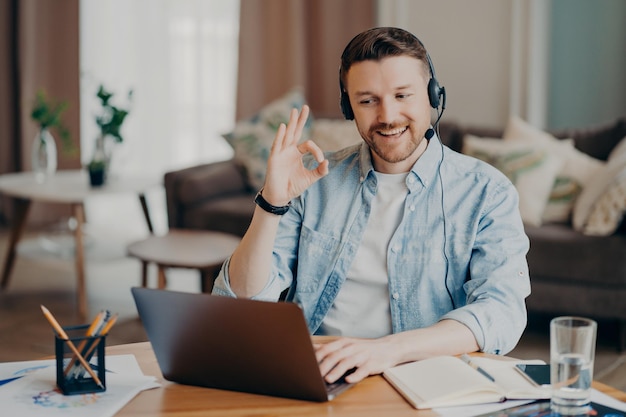 Happy young freelancer showing okay sign while having video call