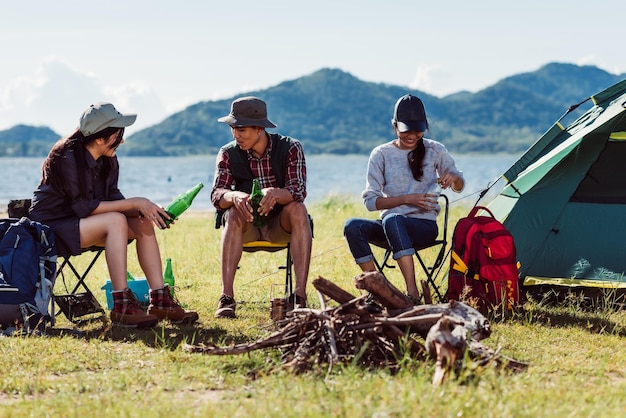 Happy young friends in camping tent party having fun together and drinking beer on holiday summer