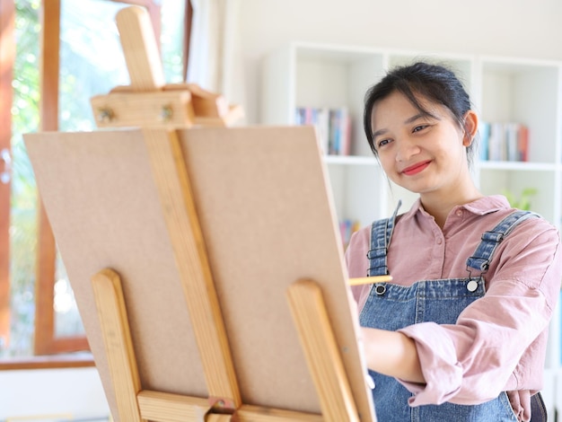 Happy young girl drawing with a paint palette and a paintbrush at homepainting artist