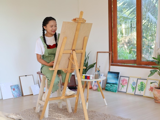 Happy young girl drawing with a paint palette and a paintbrush at homepainting artist