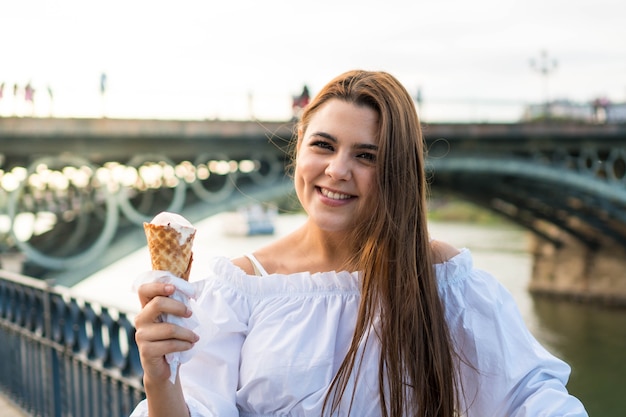 Happy young girl looking at camera and eating an ice cream in summer in Spain