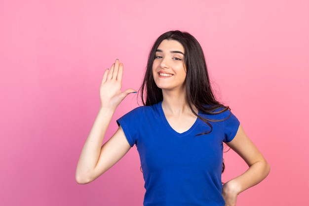 Happy young girl raised her hand and smiling